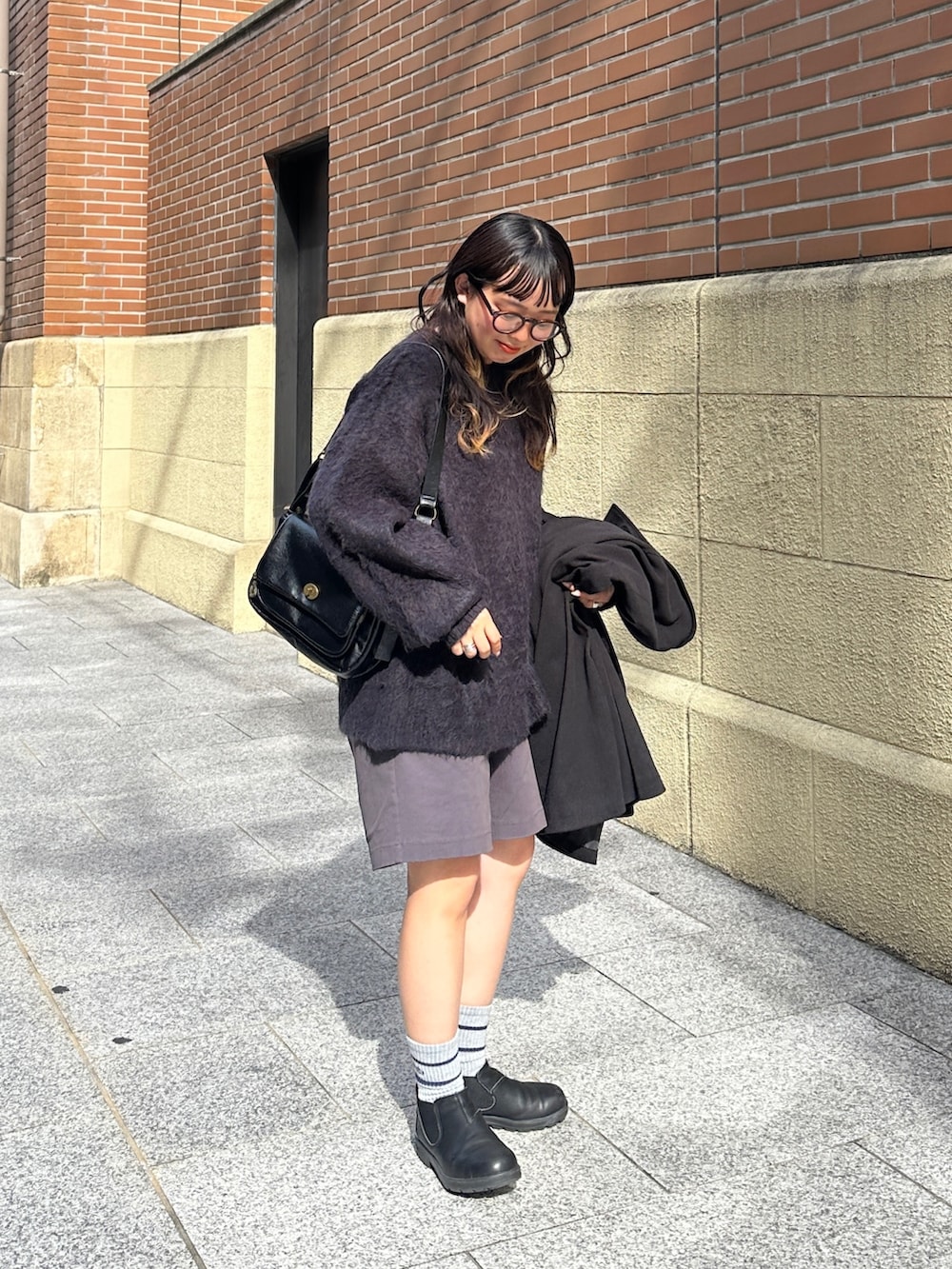 ブラック系のその他アウター、ブラック系のトートバッグ、グレー系のチノパンツを着用したレディースの秋コーディネートの2枚目の写真