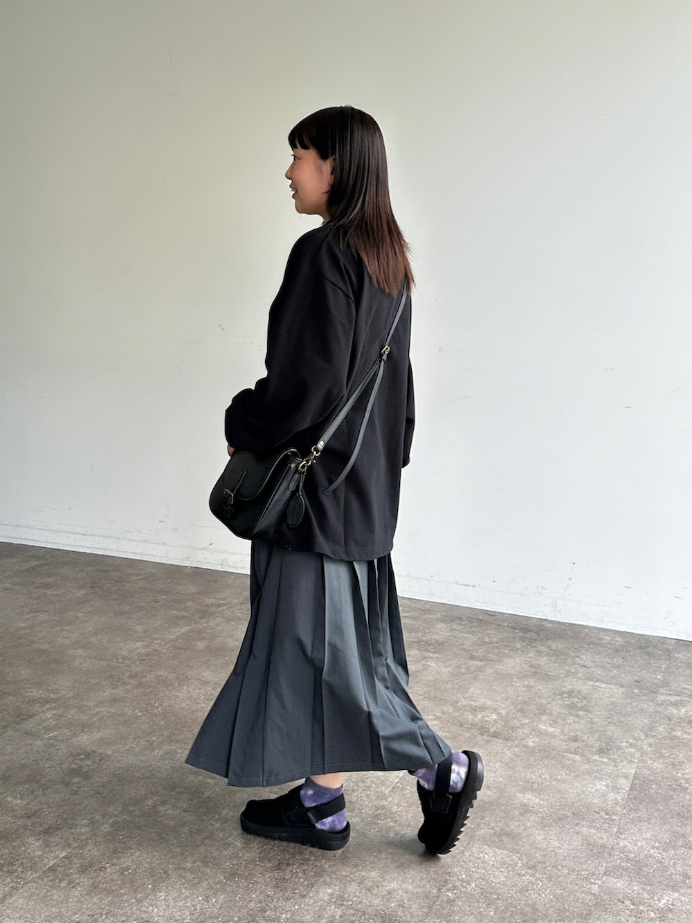 グレー系のスカート、ブラック系のサンダル、ブラック系のショルダーバッグを着用したレディースの夏コーディネートの2枚目の写真