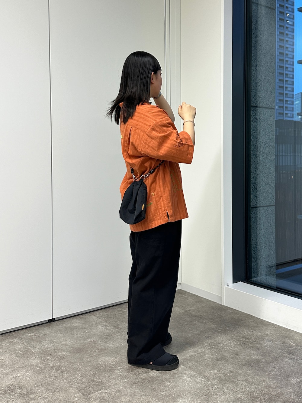 オレンジ系のシャツ/ブラウス、ブラック系のショルダーバッグ、ブラック系のその他パンツを着用したレディースの春コーディネートの2枚目の写真