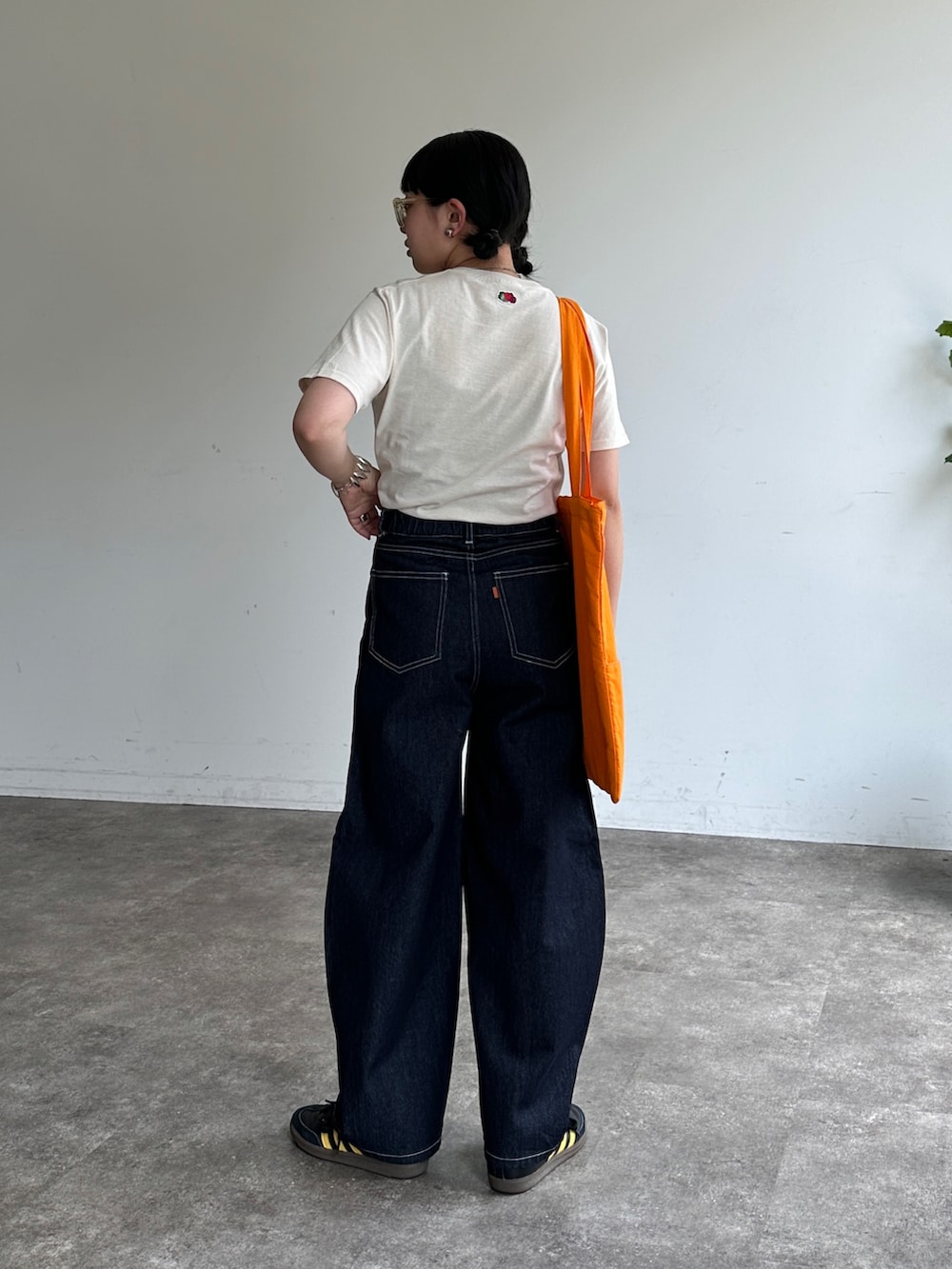 ホワイト系のTシャツ/カットソー、ブルー系のデニムパンツ、オレンジ系のトートバッグを着用したレディースの夏コーディネートの3枚目の写真