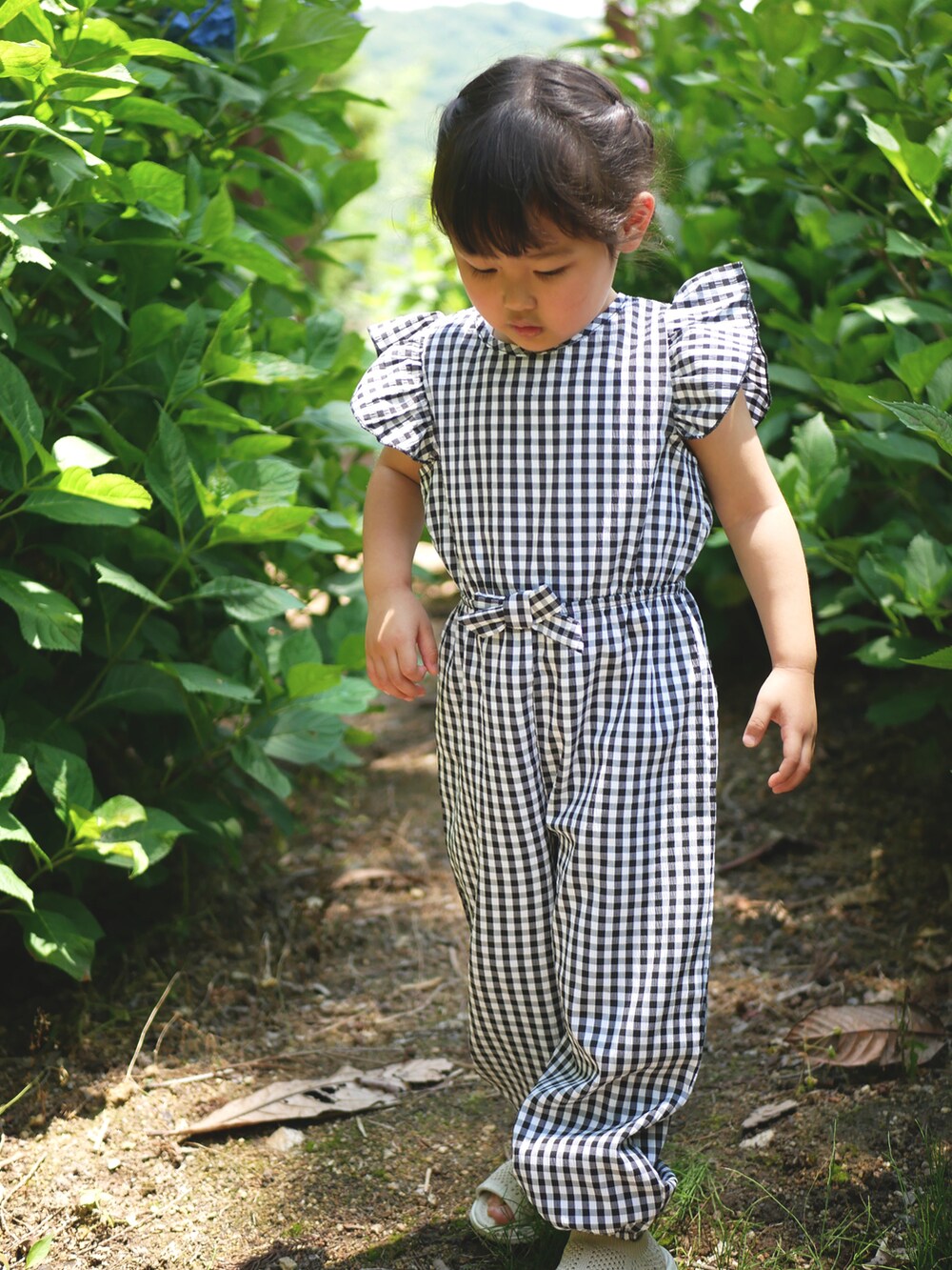 ブラック系のオールインワン・サロペット、ベージュ系のサンダルを着用したキッズの夏コーディネートの2枚目の写真