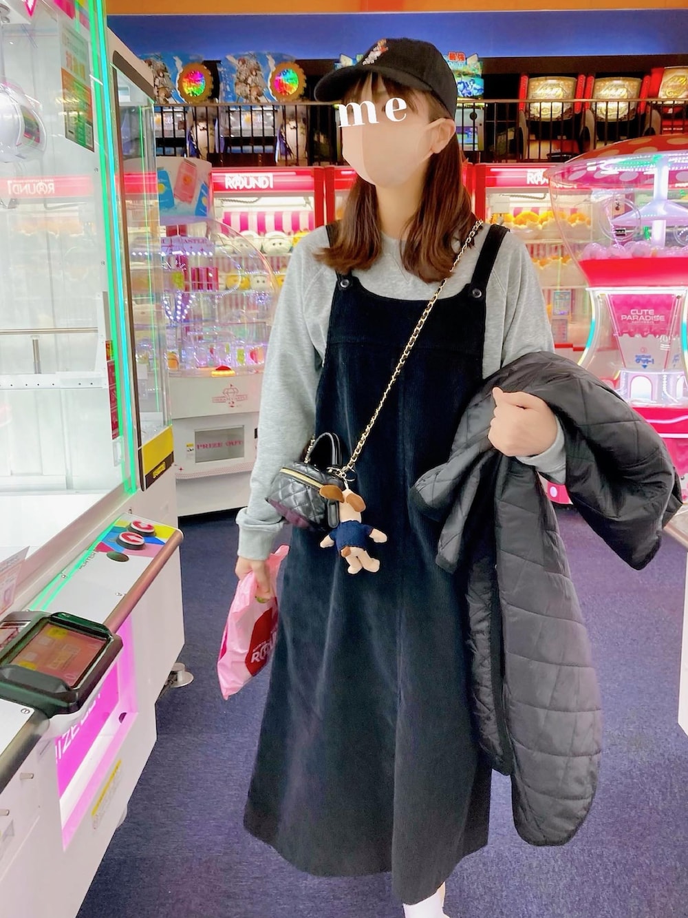 グレー系のスウェット、ブラック系のショルダーバッグ、ブラック系のジャンパースカートを着用したレディースの冬コーディネートの2枚目の写真
