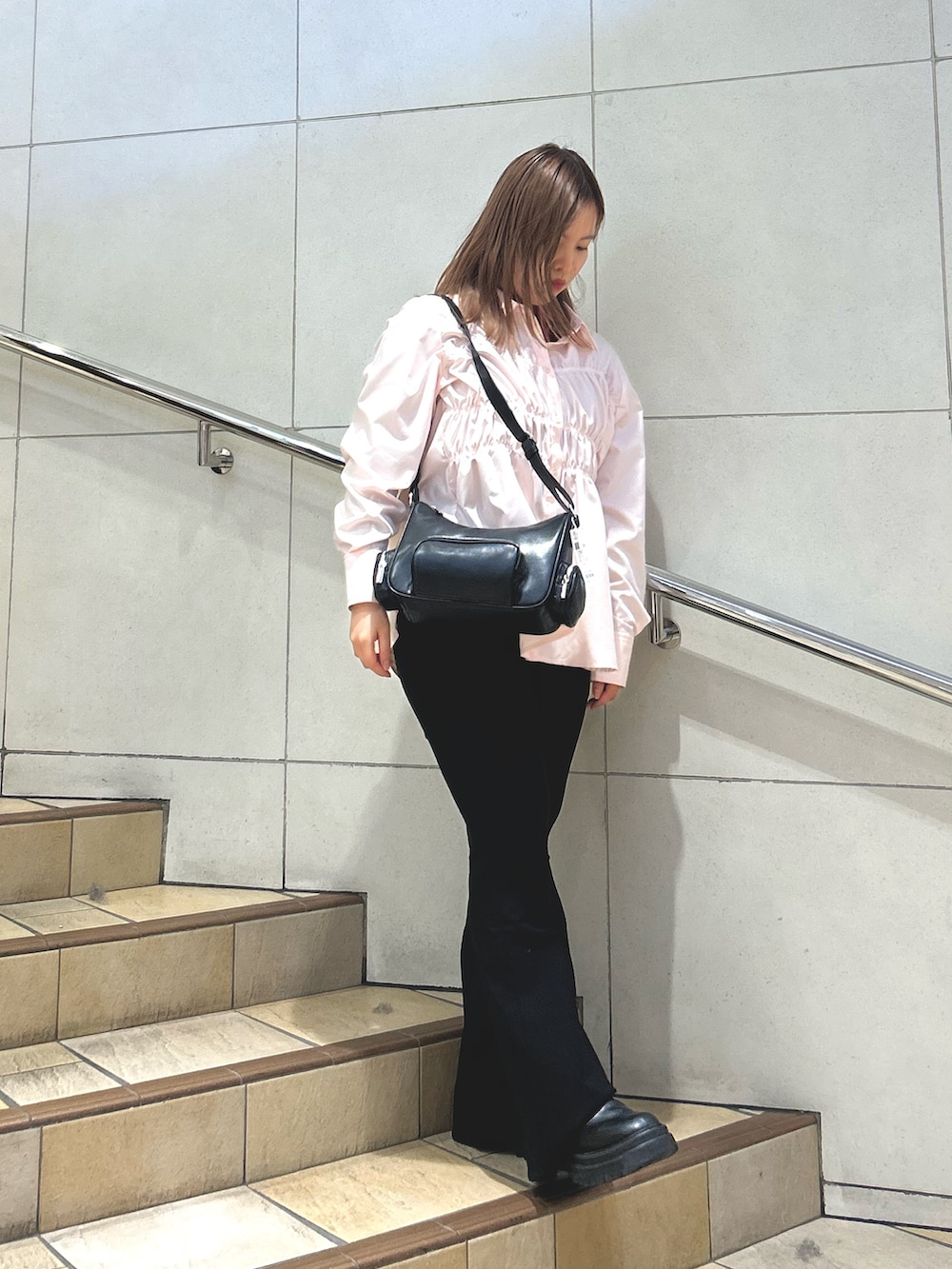 ピンク系のシャツ/ブラウス、レッド系のニット/セーター、ブラック系のショルダーバッグを着用したレディースの冬コーディネートの2枚目の写真