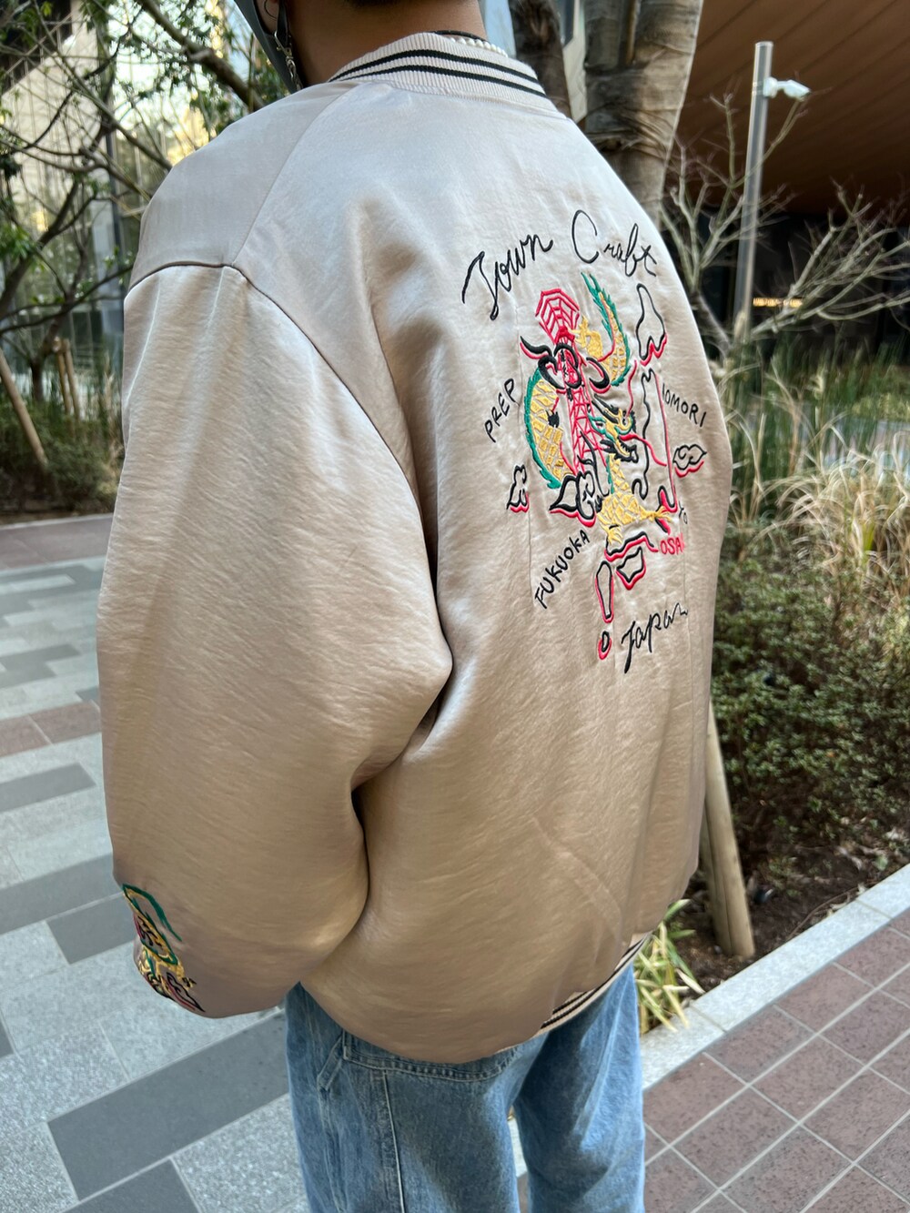 ベージュ系のブルゾン、ブルー系のデニムパンツ、ホワイト系のスニーカーを着用したメンズの春コーディネートの2枚目の写真