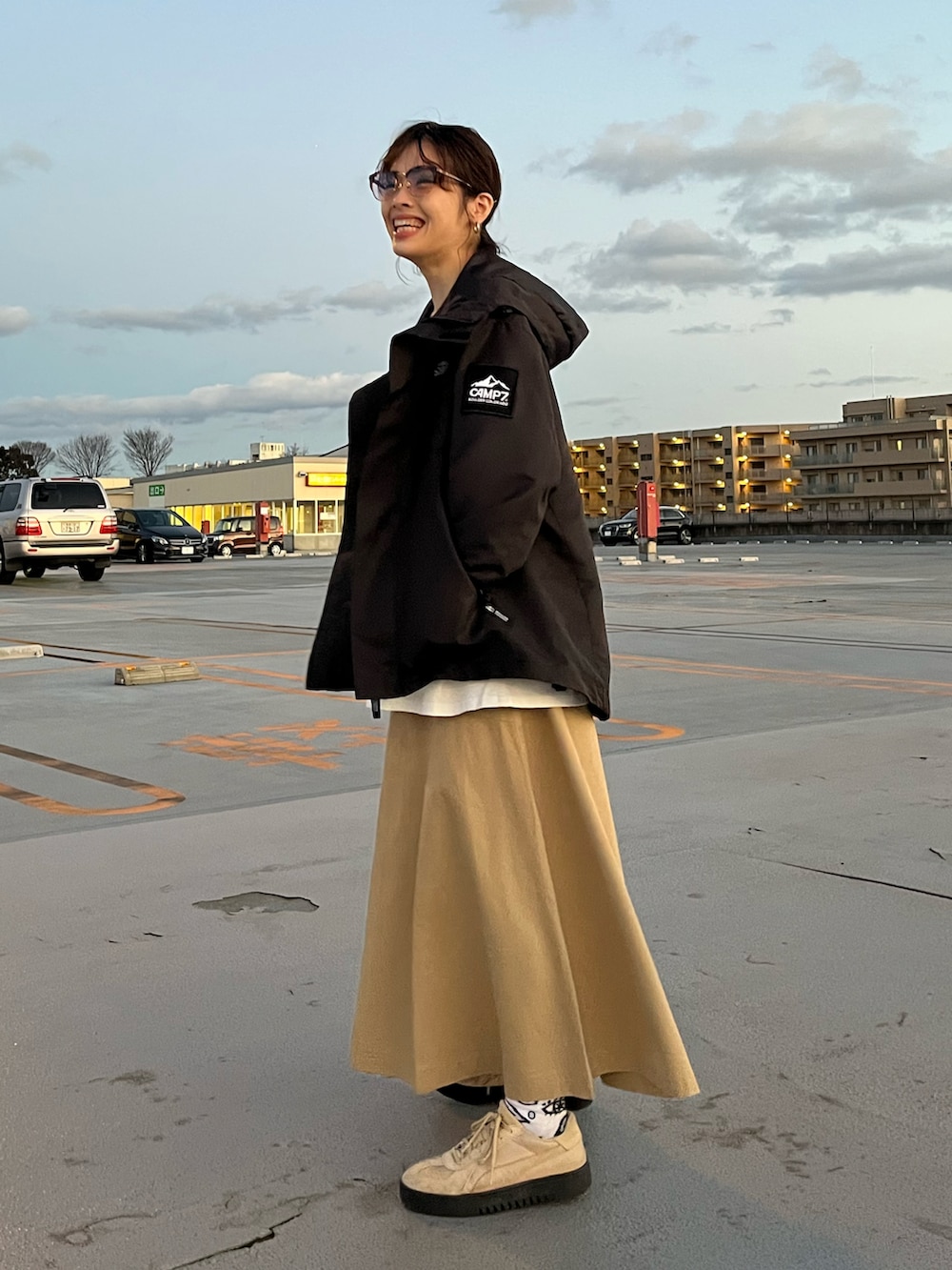 グレー系のTシャツ/カットソー、ブラック系のマウンテンパーカー、ベージュ系のスカートを着用したレディースの冬コーディネートの2枚目の写真