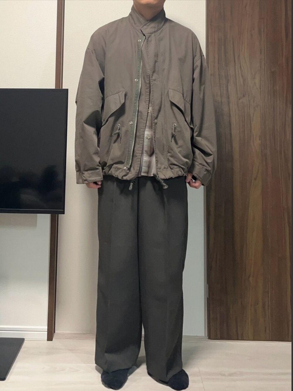 ブラウン系のスラックス、グリーン系のモッズコート、ブラウン系のシャツ/ブラウスを着用したメンズの春コーディネートの2枚目の写真