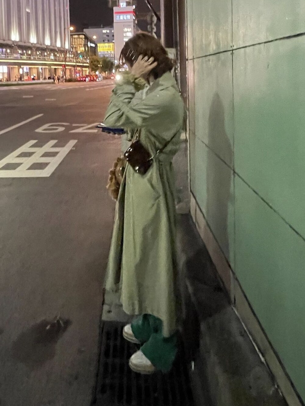 ブラウン系のショルダーバッグ、グリーン系のトレンチコートを着用したメンズの春コーディネートの2枚目の写真