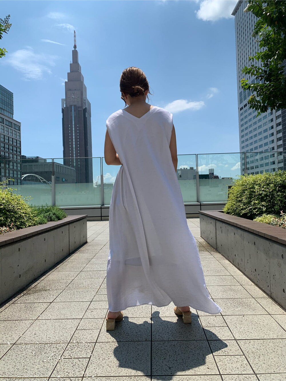 ベージュ系のサンダル、ホワイト系のワンピース、オレンジ系のカーディガン/ボレロを着用したレディースの夏コーディネートの3枚目の写真