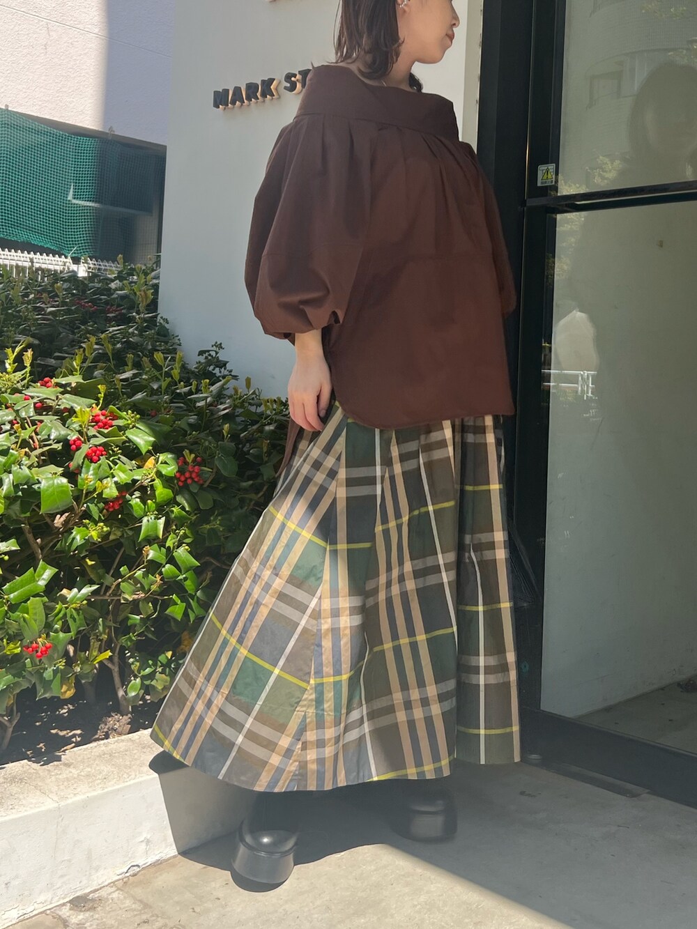 グリーン系のスカート、ブラウン系のシャツ/ブラウス、ブラック系のハンドバッグを着用したレディースの春コーディネートの2枚目の写真