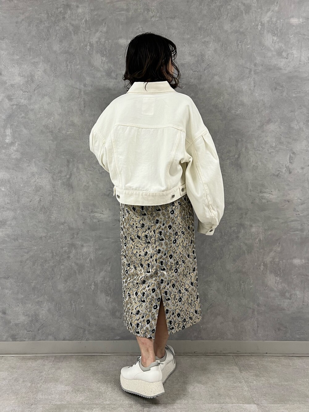 ホワイト系のデニムジャケット、グリーン系のニット/セーター、ベージュ系のスカートを着用したレディースの冬コーディネートの3枚目の写真