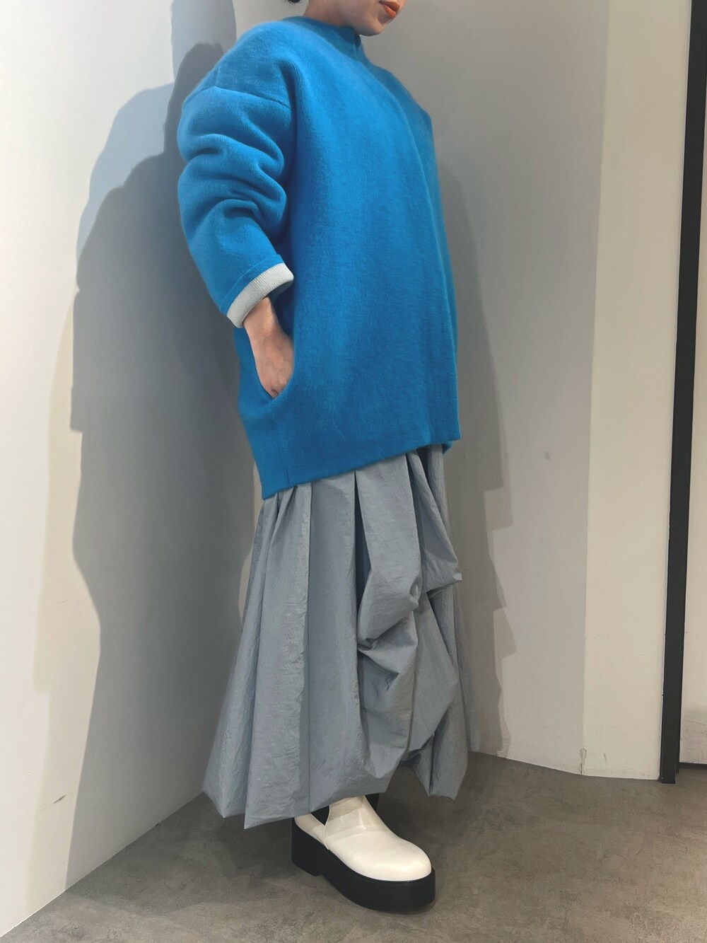 ブルー系のノーカラージャケット、ブルー系のスカート、ホワイト系のブーツを着用したレディースの夏コーディネートの3枚目の写真