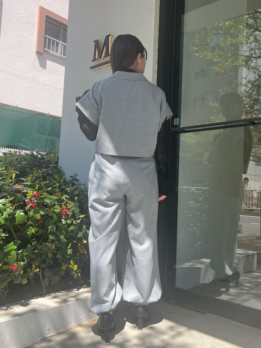 グレー系のテーラードジャケット、グレー系のスラックス、ブラック系のパンプスを着用したレディースの春コーディネートの3枚目の写真