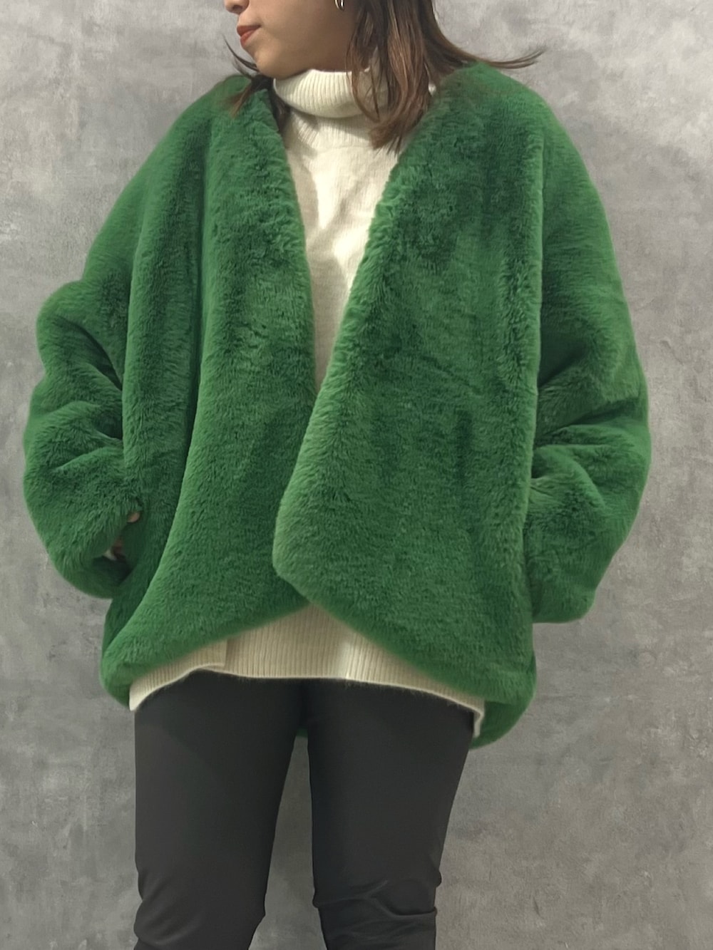 グリーン系のノーカラーコート、ホワイト系のニット/セーター、グレー系のその他パンツを着用したレディースの秋コーディネートの3枚目の写真