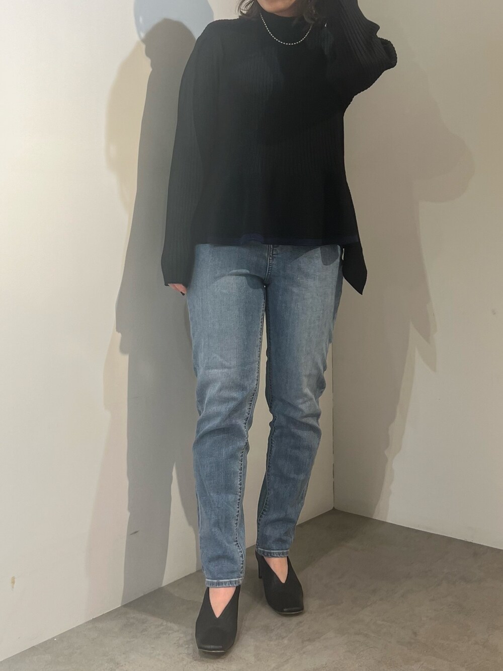 ベージュ系のトレンチコート、ブラック系のニット/セーター、ブルー系のデニムパンツを着用したレディースの冬コーディネートの7枚目の写真