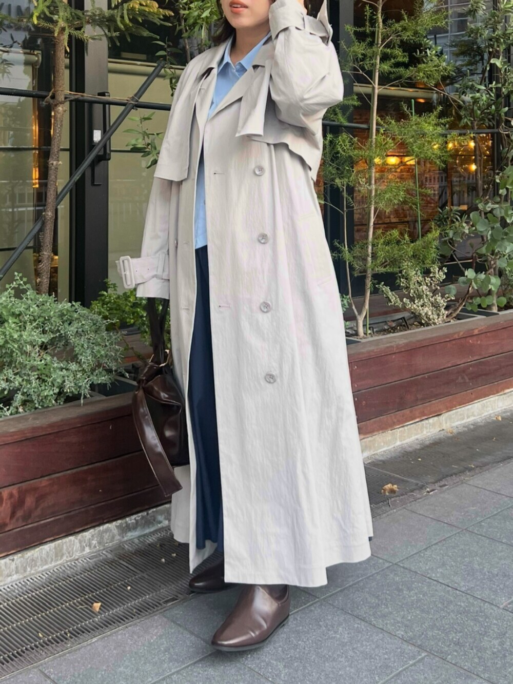 ブラック系のブーツ、グレー系のトレンチコート、ブラウン系のハンドバッグを着用したレディースの冬コーディネートの3枚目の写真