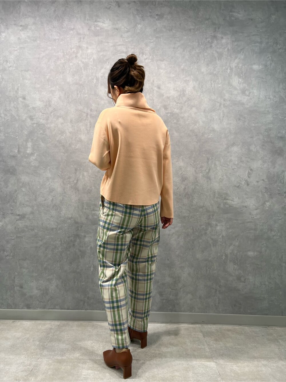 ブラウン系のブーツ、グリーン系のその他パンツ、オレンジ系のニット/セーターを着用したレディースの冬コーディネートの5枚目の写真