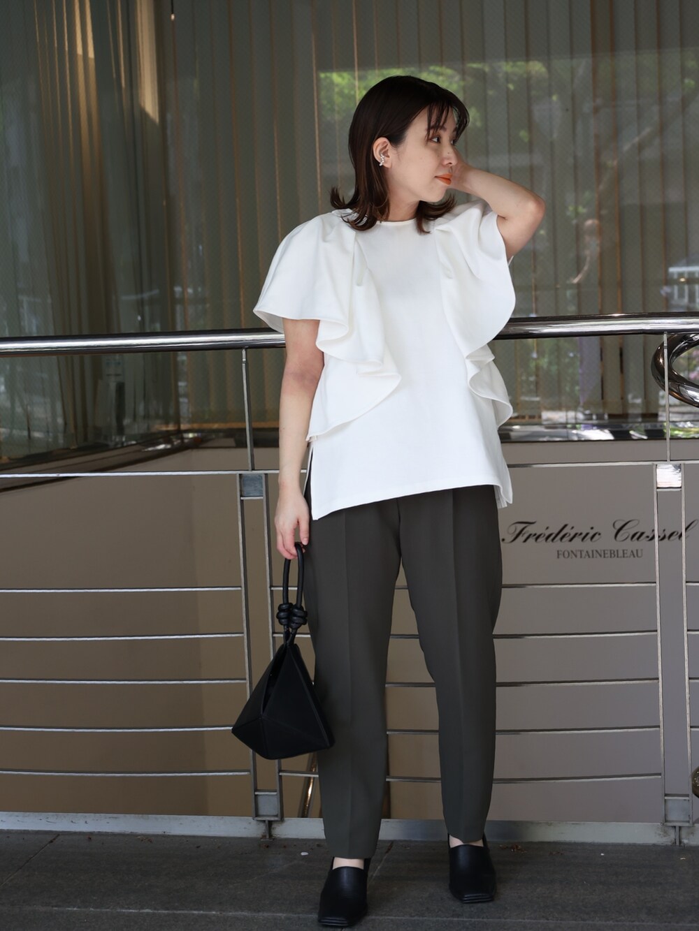 ホワイト系のTシャツ/カットソー、ブラック系のハンドバッグ、ブラック系のパンプスを着用したレディースの夏コーディネートの2枚目の写真