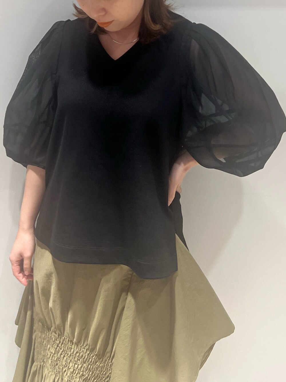 グリーン系のスカート、ブラック系のTシャツ/カットソー、ホワイト系のブーツを着用したレディースの春コーディネートの3枚目の写真