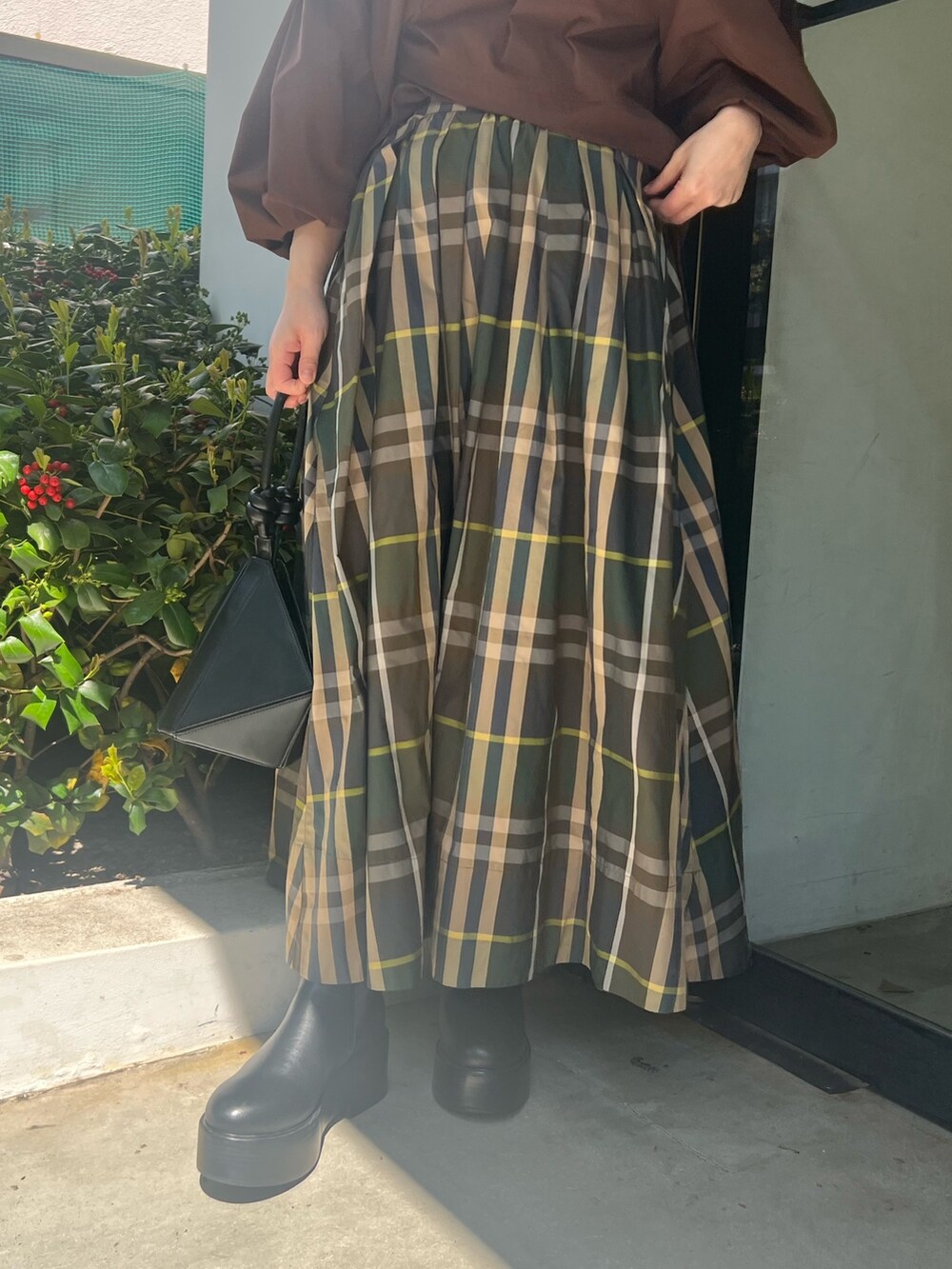 グリーン系のスカート、ブラウン系のシャツ/ブラウス、ブラック系のハンドバッグを着用したレディースの春コーディネートの5枚目の写真