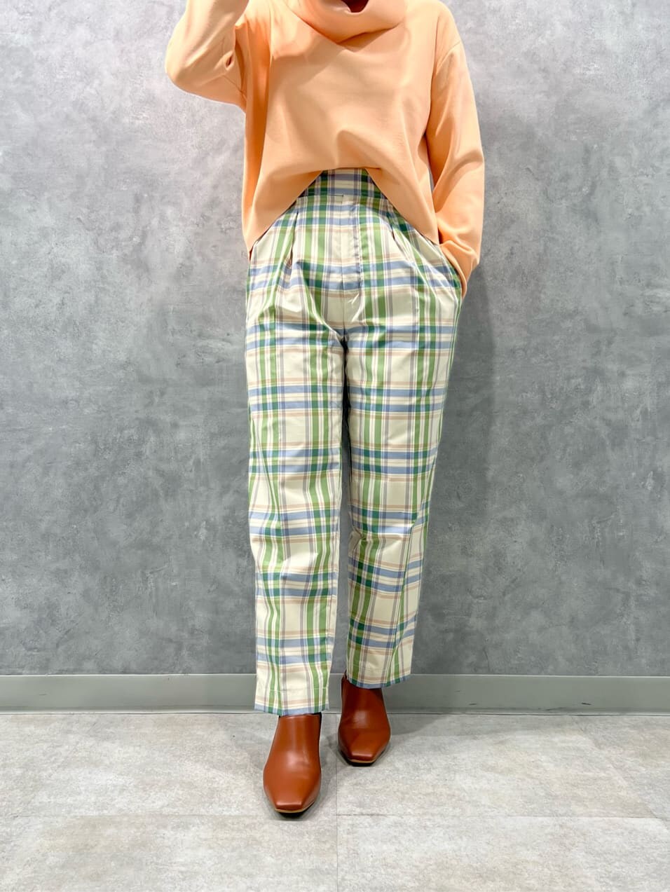 ブラウン系のブーツ、グリーン系のその他パンツ、オレンジ系のニット/セーターを着用したレディースの冬コーディネートの3枚目の写真