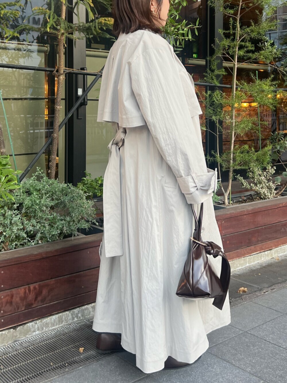 ブラック系のブーツ、グレー系のトレンチコート、ブラウン系のハンドバッグを着用したレディースの冬コーディネートの4枚目の写真