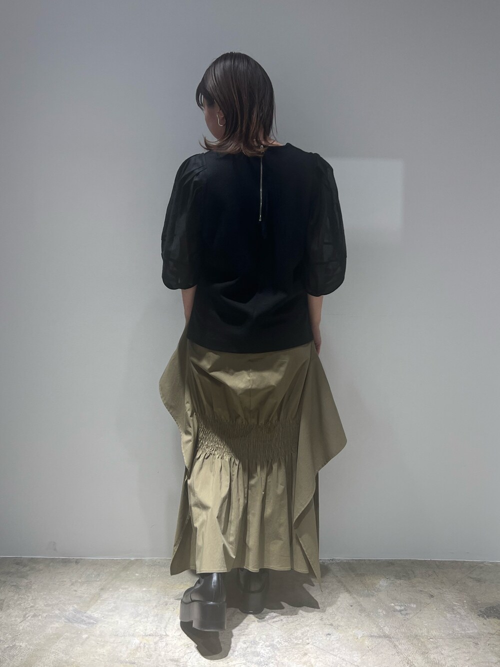 グリーン系のスカート、ブラック系のTシャツ/カットソー、ホワイト系のブーツを着用したレディースの春コーディネートの4枚目の写真