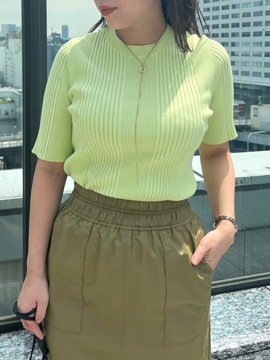 ベージュ系のスカート、ブルー系のスニーカー、グリーン系のニット/セーターを着用したレディースの夏コーディネートの3枚目の写真