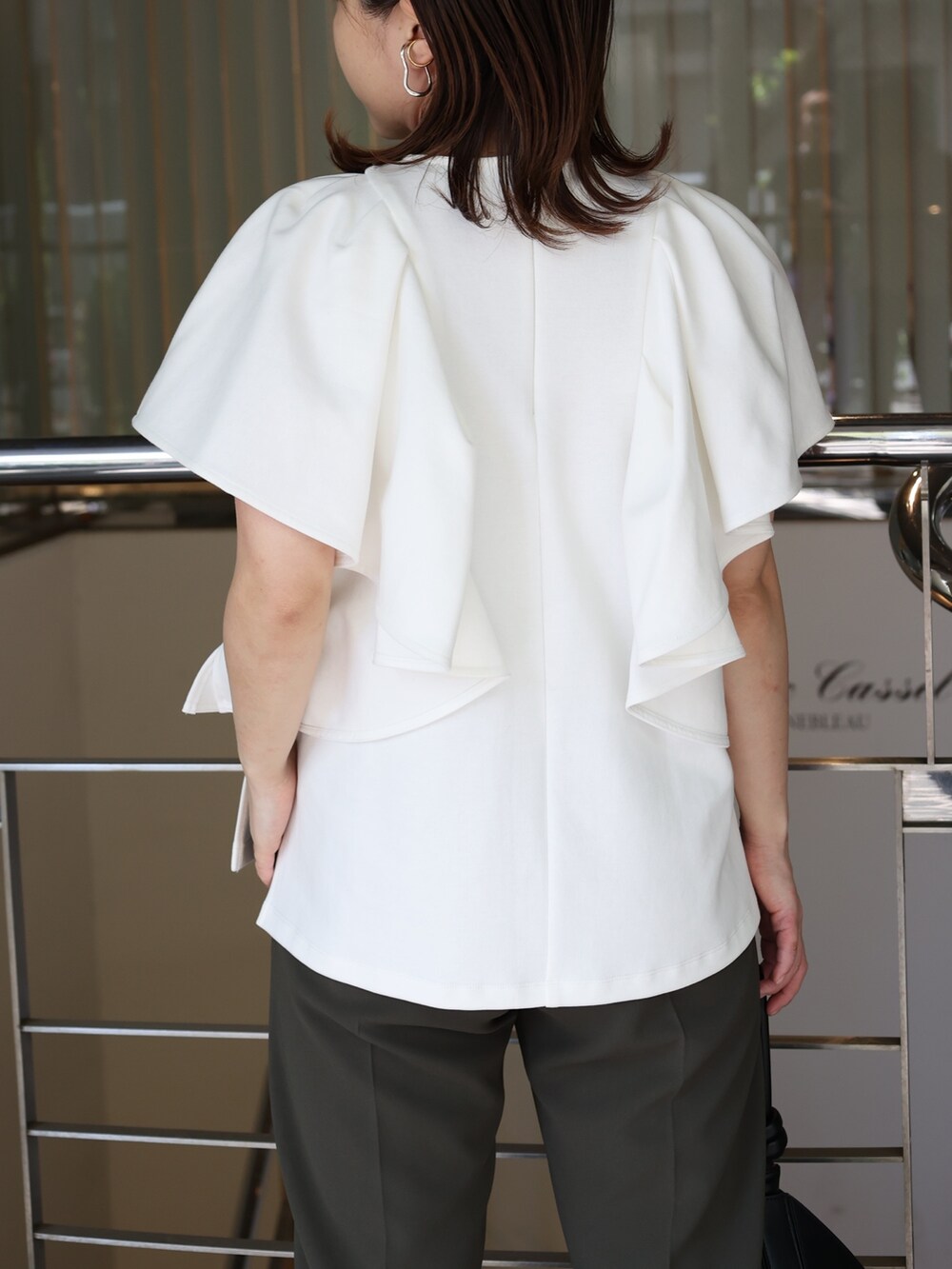 ホワイト系のTシャツ/カットソー、ブラック系のハンドバッグ、ブラック系のパンプスを着用したレディースの夏コーディネートの5枚目の写真