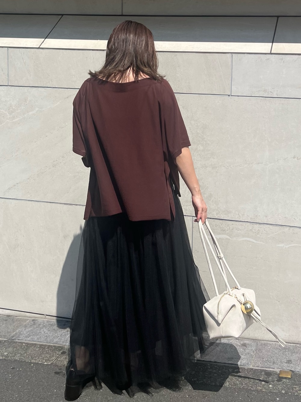 ブラック系のパンプス、ブラウン系のニット/セーター、ブラック系のスカートを着用したレディースの夏コーディネートの4枚目の写真