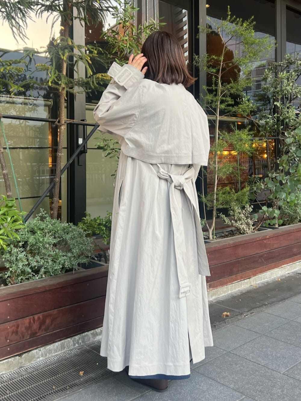 ブラック系のブーツ、グレー系のトレンチコート、ブラウン系のハンドバッグを着用したレディースの冬コーディネートの2枚目の写真