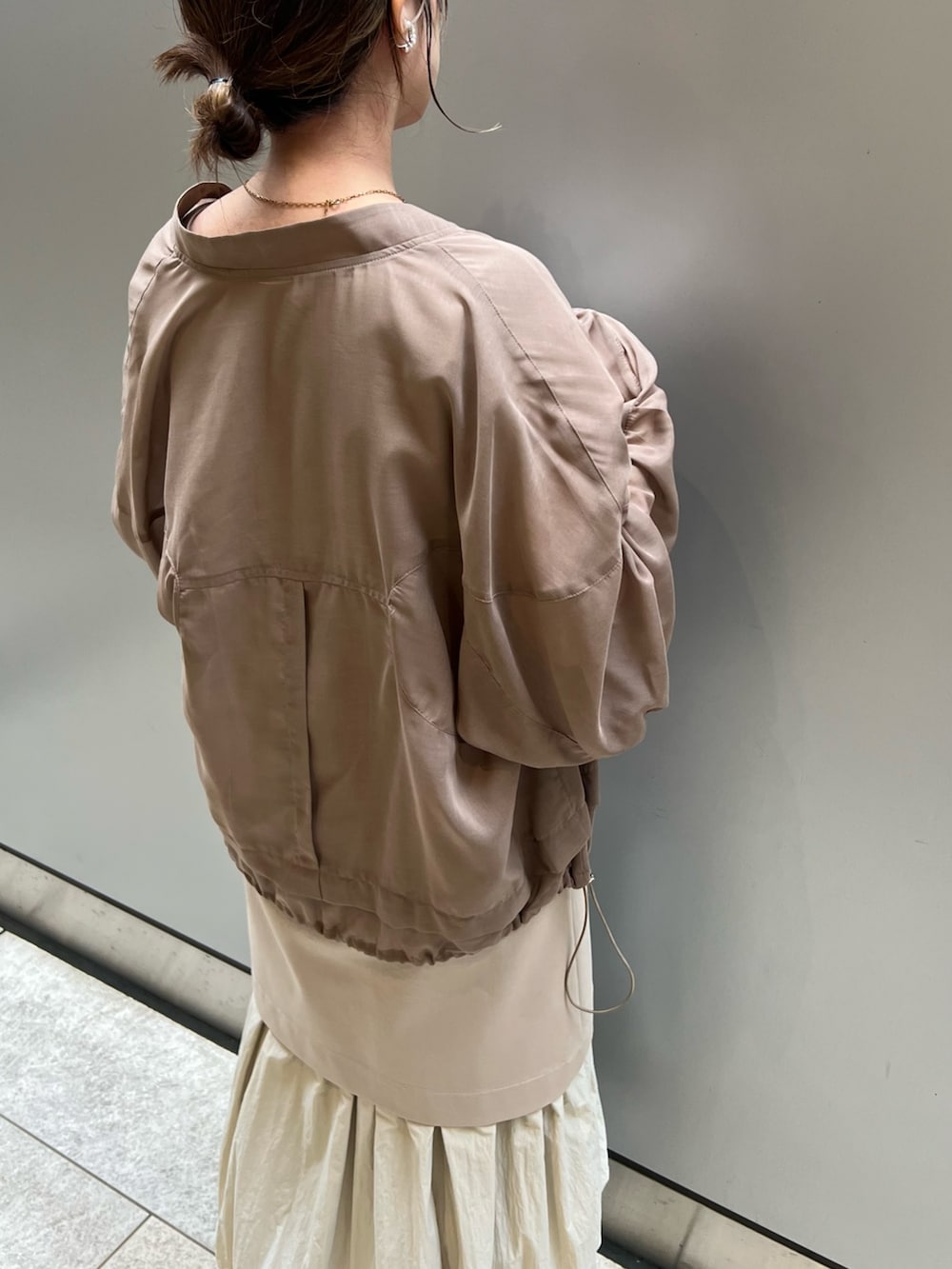 ベージュ系のワンピース、ホワイト系のスニーカー、ブラウン系のブルゾンを着用したレディースの春コーディネートの3枚目の写真