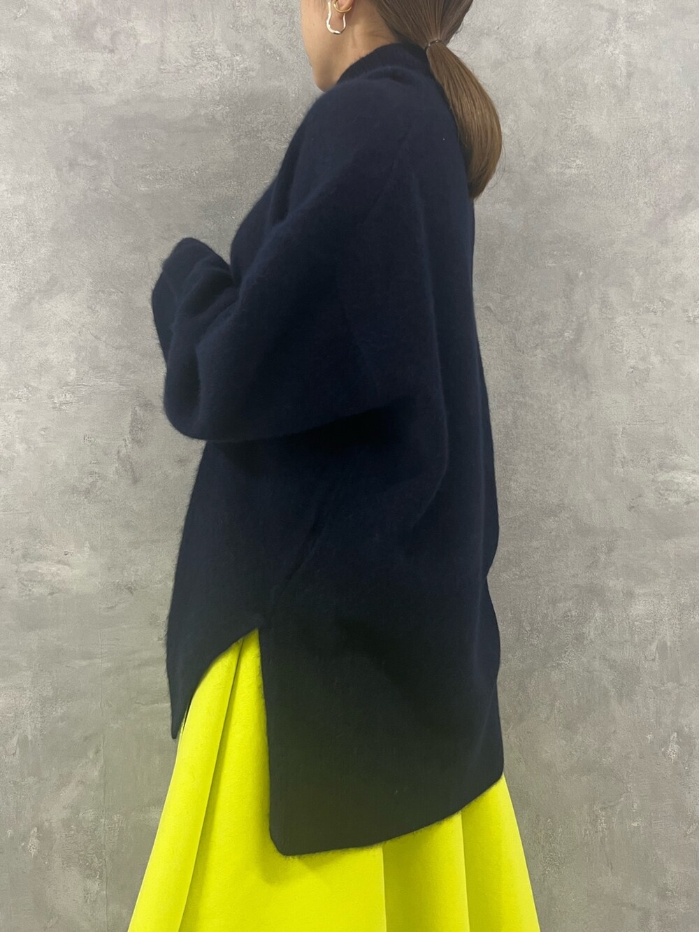 ブルー系のニット/セーター、ベージュ系のハンドバッグ、イエロー系のスカートを着用したレディースの秋コーディネートの5枚目の写真