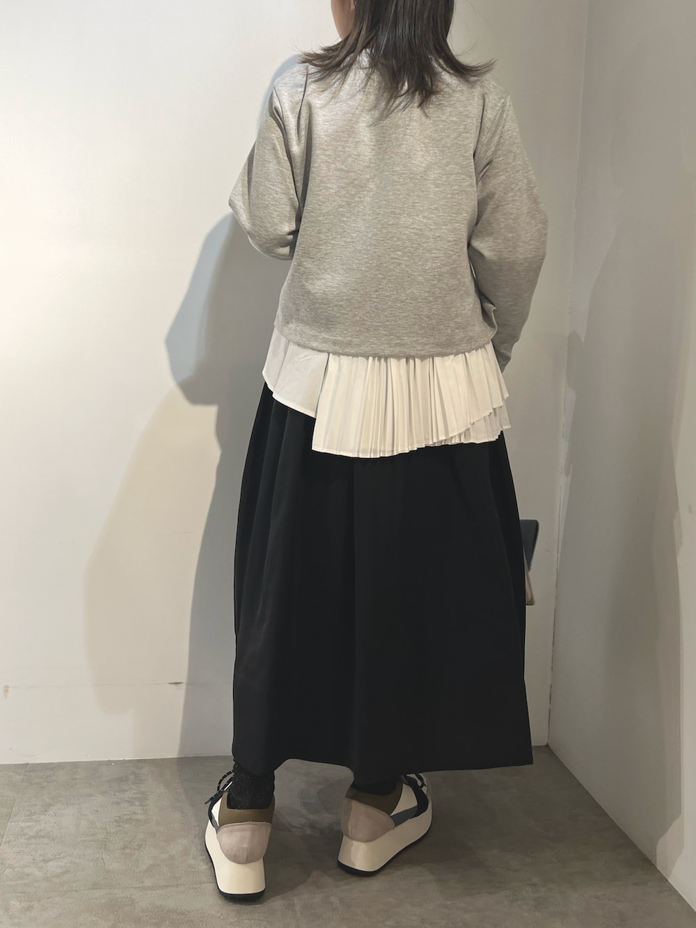 グレー系のTシャツ/カットソー、ブラック系のスカート、ブルー系のスニーカーを着用したレディースの冬コーディネートの4枚目の写真