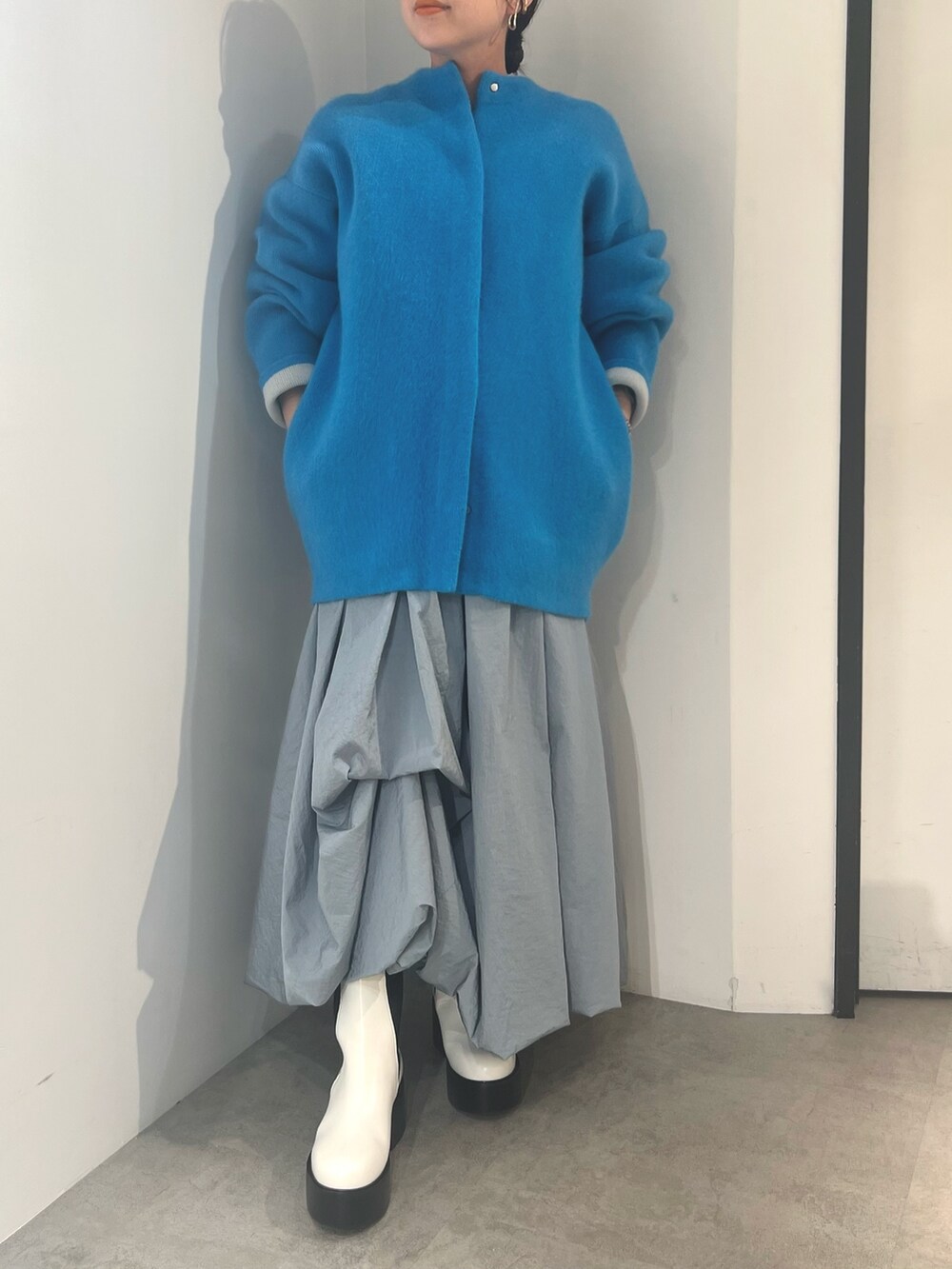 ブルー系のノーカラージャケット、ブルー系のスカート、ホワイト系のブーツを着用したレディースの夏コーディネートの2枚目の写真