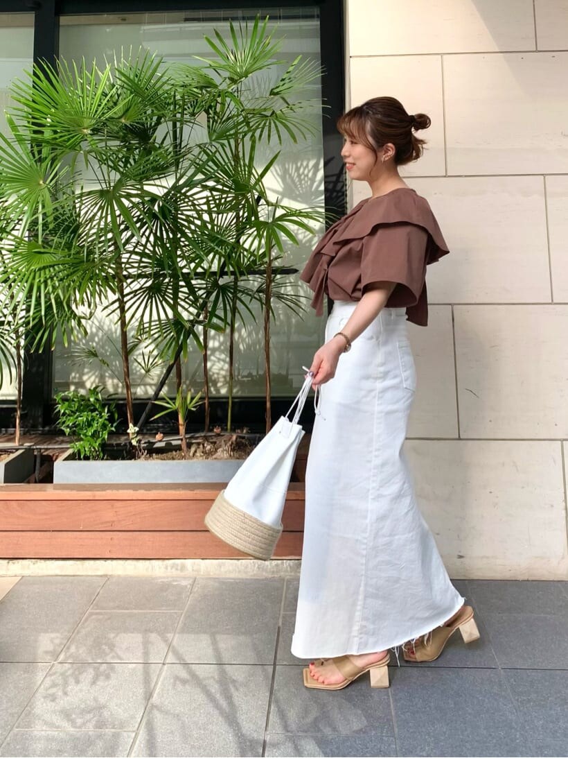 ホワイト系のデニムスカート、ベージュ系のサンダル、ホワイト系のハンドバッグを着用したレディースの夏コーディネートの4枚目の写真