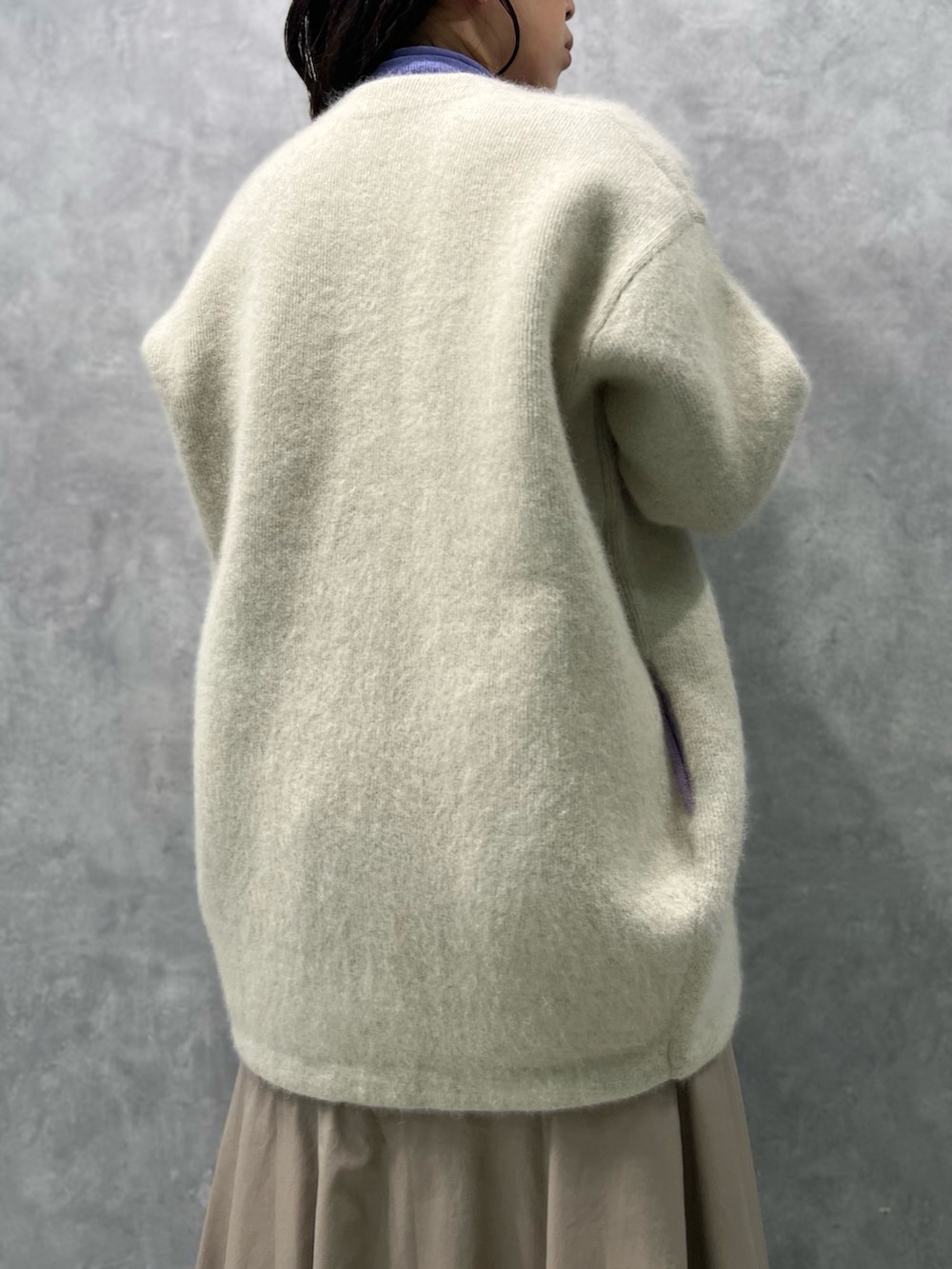 ホワイト系のノーカラージャケット、パープル系のニット/セーター、ベージュ系のスカートを着用したレディースの夏コーディネートの6枚目の写真