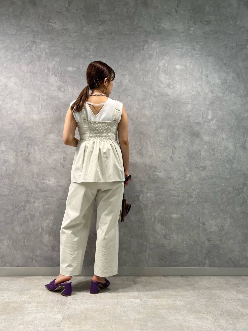 ホワイト系のタンクトップ、ベージュ系のキャミソール、パープル系のサンダルを着用したレディースの春コーディネートの2枚目の写真