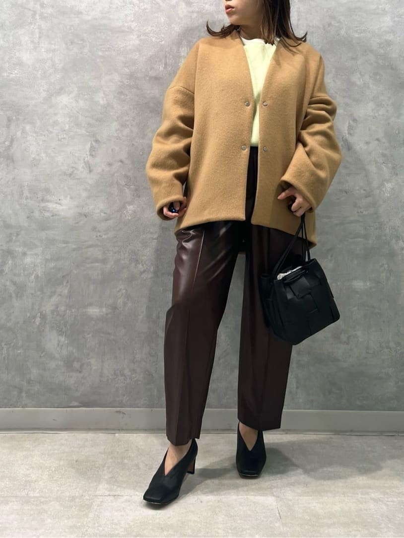 イエロー系のノーカラーコート、ブラウン系のその他パンツ、ホワイト系のニット/セーターを着用したレディースの秋コーディネートの3枚目の写真