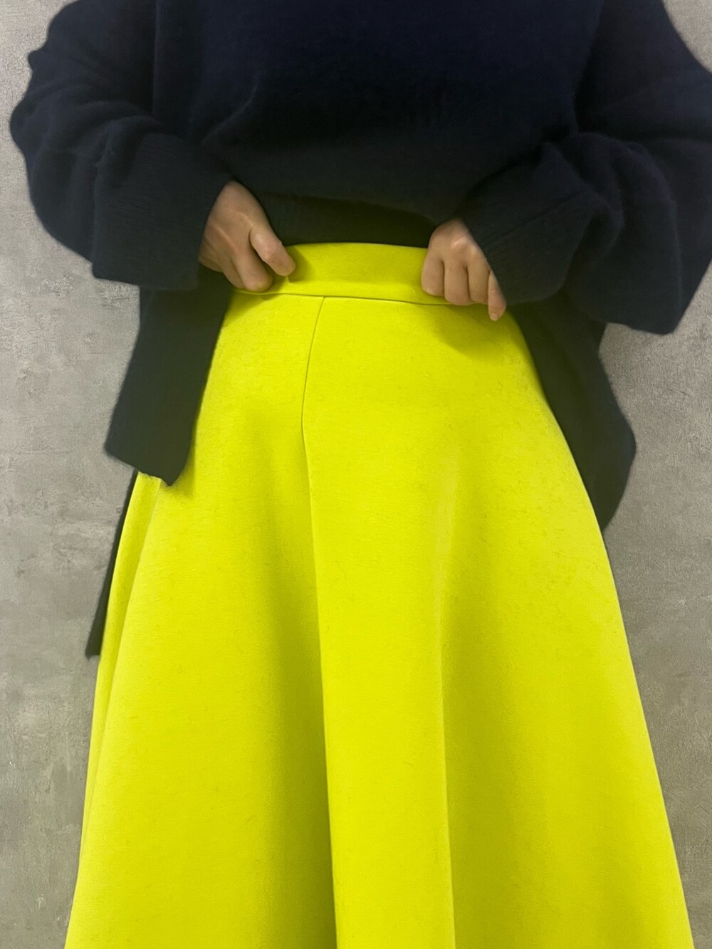 ブルー系のニット/セーター、ベージュ系のハンドバッグ、イエロー系のスカートを着用したレディースの秋コーディネートの6枚目の写真