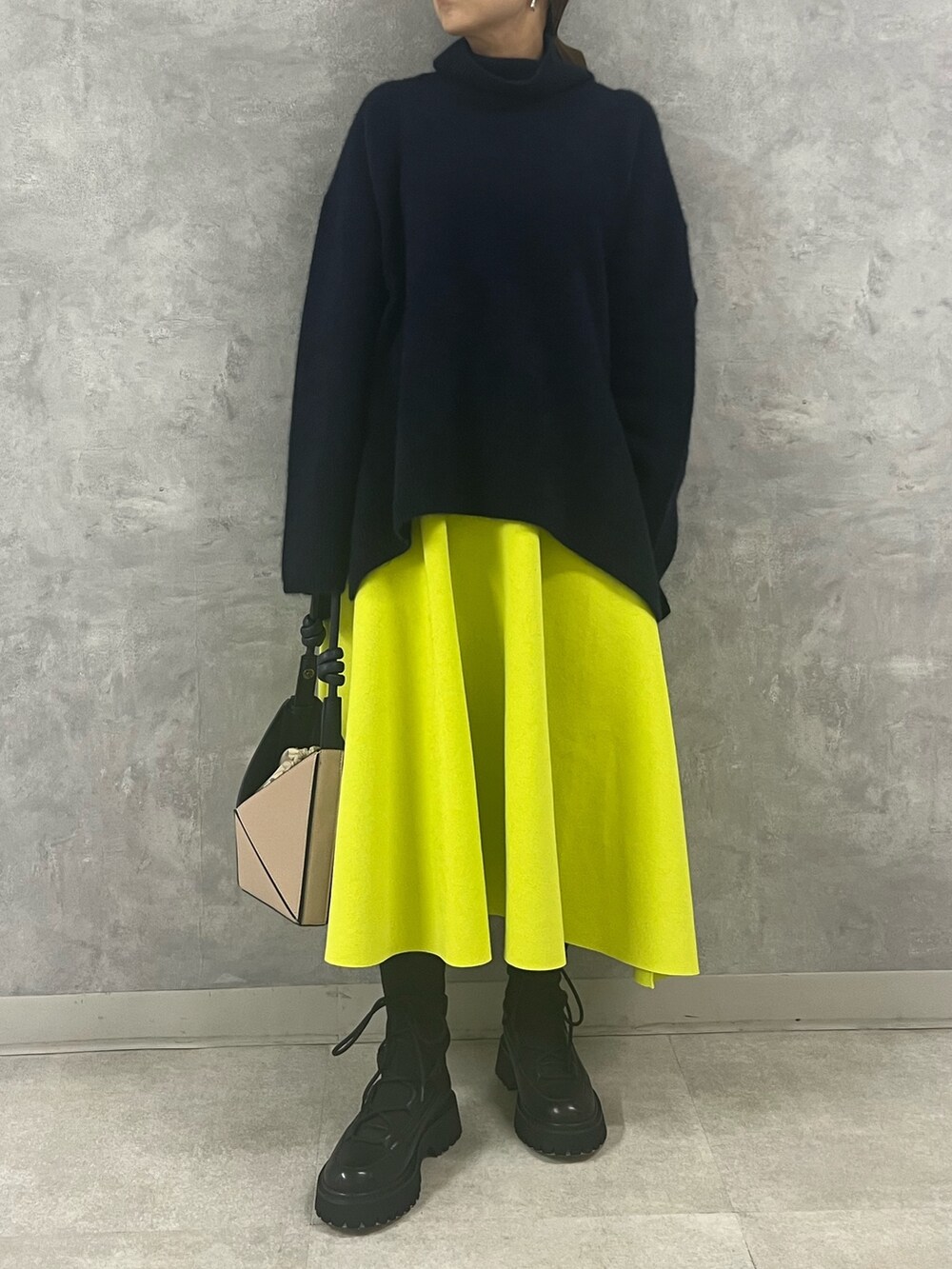 ブルー系のニット/セーター、ベージュ系のハンドバッグ、イエロー系のスカートを着用したレディースの秋コーディネートの7枚目の写真