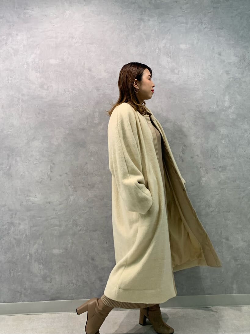 ベージュ系のワンピース、ホワイト系のハンドバッグ、ベージュ系のノーカラーコートを着用したレディースの秋コーディネートの3枚目の写真