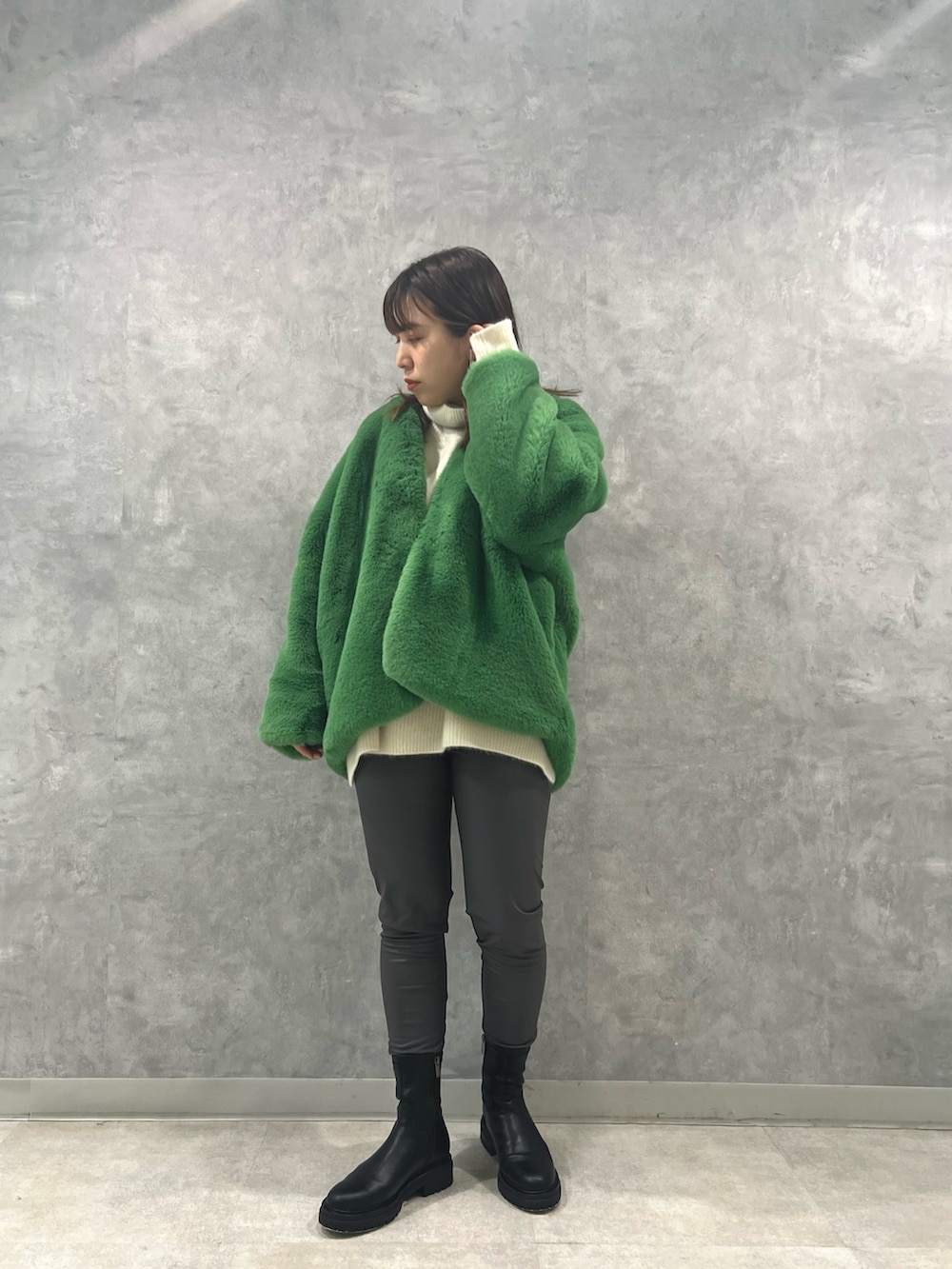 グリーン系のノーカラーコート、ホワイト系のニット/セーター、グレー系のその他パンツを着用したレディースの秋コーディネートの2枚目の写真