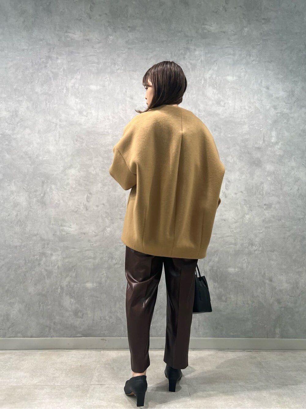 イエロー系のノーカラーコート、ブラウン系のその他パンツ、ホワイト系のニット/セーターを着用したレディースの秋コーディネートの2枚目の写真