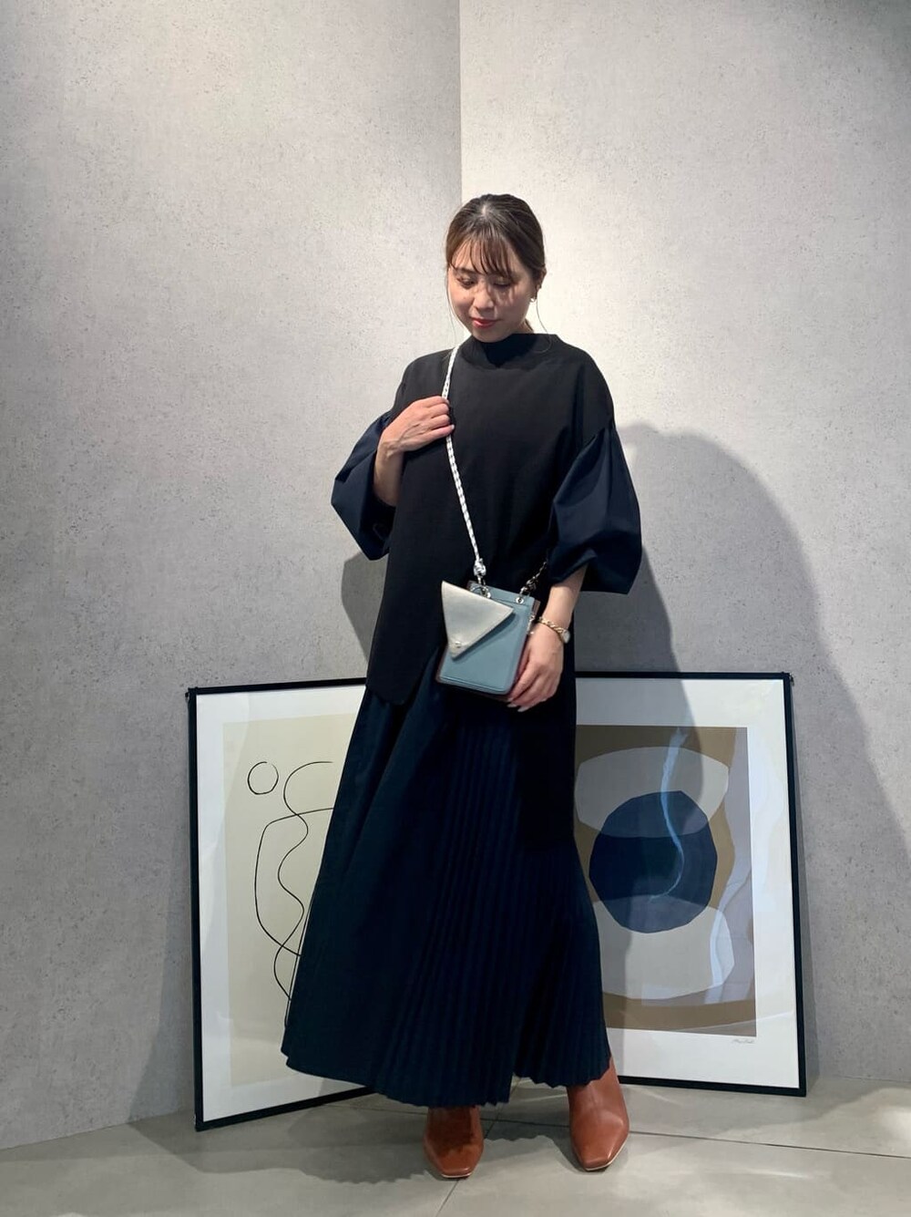 ブラウン系のショルダーバッグ、ブラック系のワンピース、ブラウン系のブーツを着用したレディースの夏コーディネートの2枚目の写真