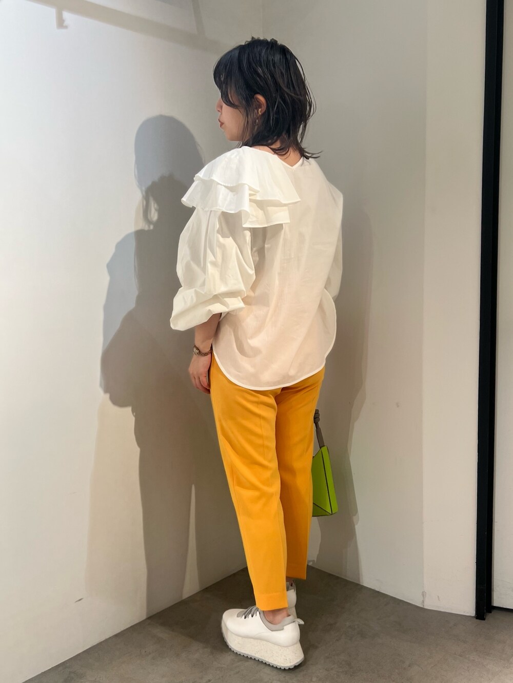 ホワイト系のシャツ/ブラウス、イエロー系のハンドバッグ、オレンジ系のその他パンツを着用したレディースの冬コーディネートの2枚目の写真