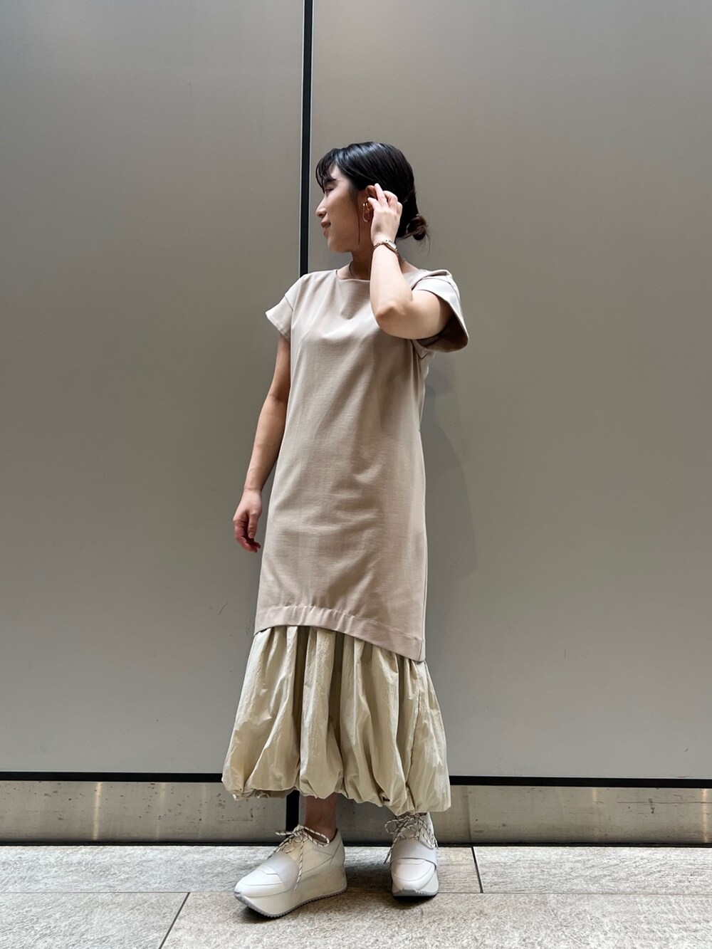 ベージュ系のワンピース、ホワイト系のスニーカー、ブラウン系のブルゾンを着用したレディースの春コーディネートの5枚目の写真
