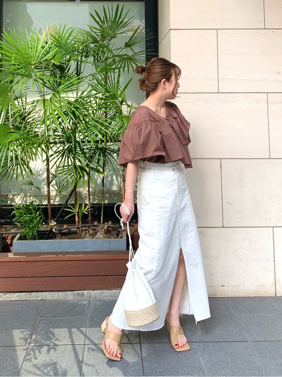 ホワイト系のデニムスカート、ベージュ系のサンダル、ホワイト系のハンドバッグを着用したレディースの夏コーディネートの2枚目の写真