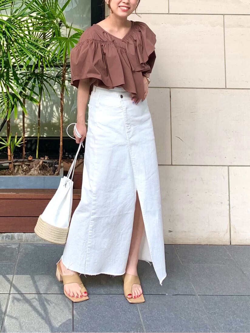 ホワイト系のデニムスカート、ベージュ系のサンダル、ホワイト系のハンドバッグを着用したレディースの夏コーディネートの3枚目の写真