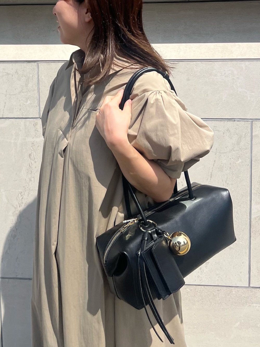 ベージュ系のワンピース、ブラック系のボストンバッグ、ブラック系のパンプスを着用したレディースの夏コーディネートの5枚目の写真