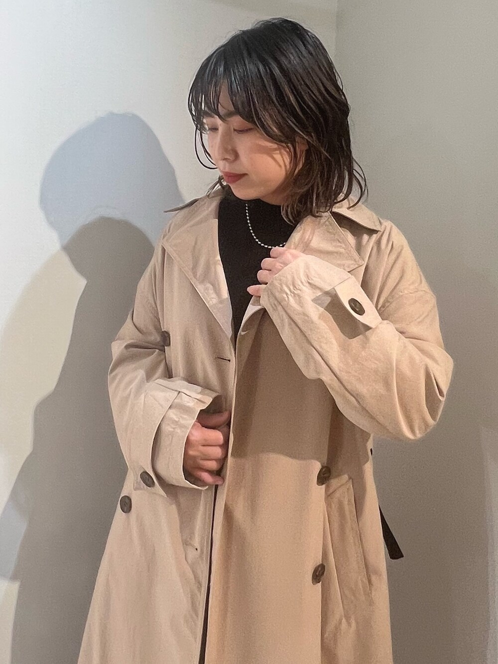 ベージュ系のトレンチコート、ブラック系のニット/セーター、ブルー系のデニムパンツを着用したレディースの冬コーディネートの4枚目の写真